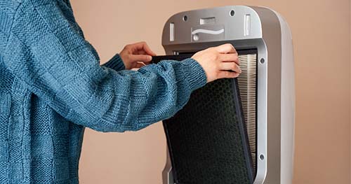 Image: A woman changing the air filter in her air purifier.
