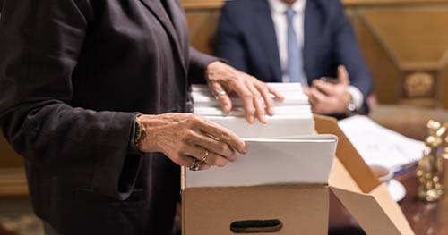 Image: a woman going through a cardboard box full of important documents.