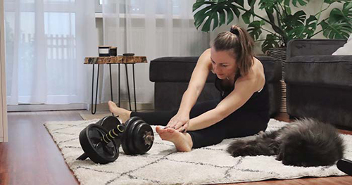 Image: a woman and her cat stretch before a workout.