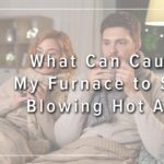 Image: a couple is bundled up on the couch drinking hot beverages, cover image for What Can Cause My Furnace to Stop Blowing Hot Air?