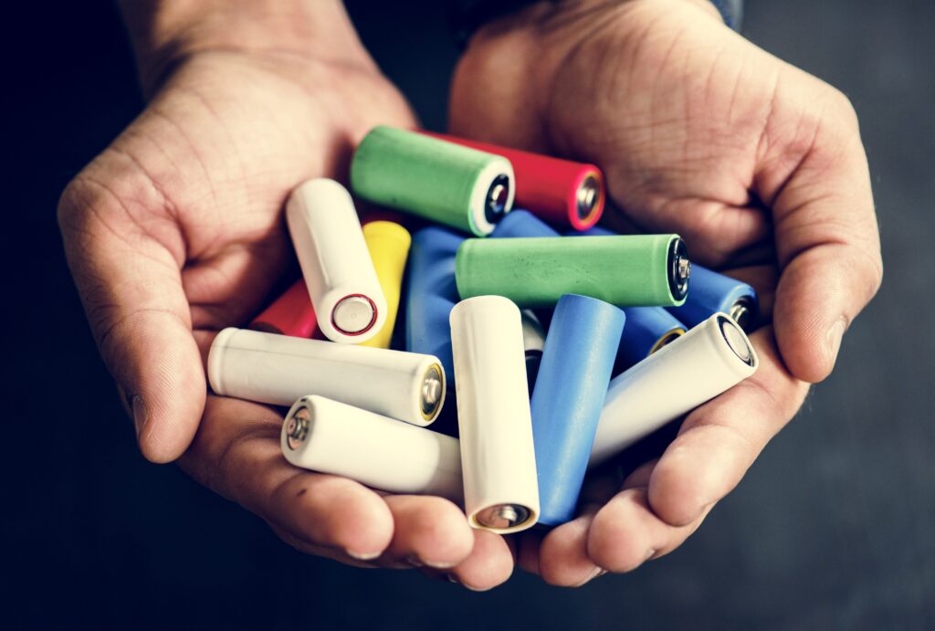 Hands holding various alkaline battery